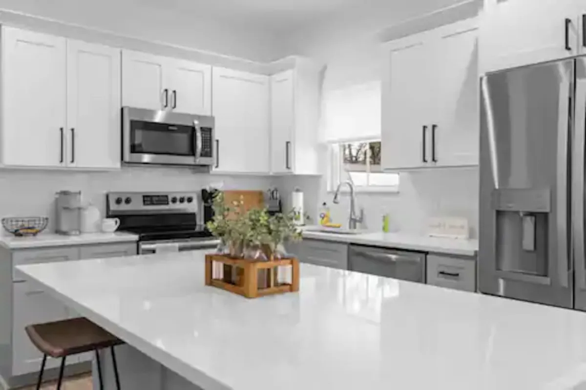 A contemporary kitchen with an island countertop, stainless steel appliances, and a vase of fresh flowers adding a touch of home. The design is open and welcoming, with space for both cooking and casual dining or entertaining.